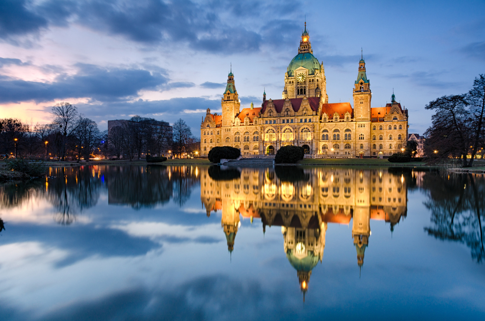 Das Neue Rathaus Hannover in der Dämmerung, beleuchtet, davor der Maschteich; Observationen durch Detektive der Kurtz Detektei Hannover, Privatdetektiv Hannover, Privatermittler Hannover, Detektivagentur Hannover